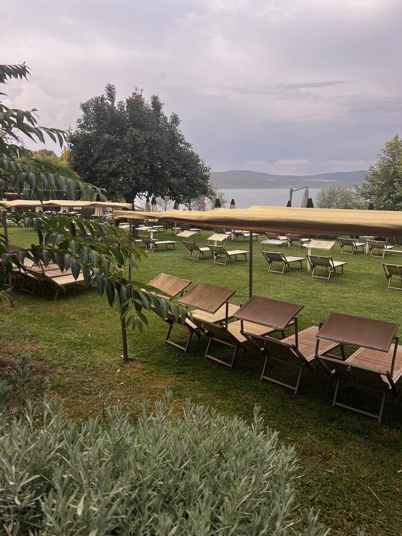Dřevěná lehátka se stínícími plachtami a výhledem na jezero